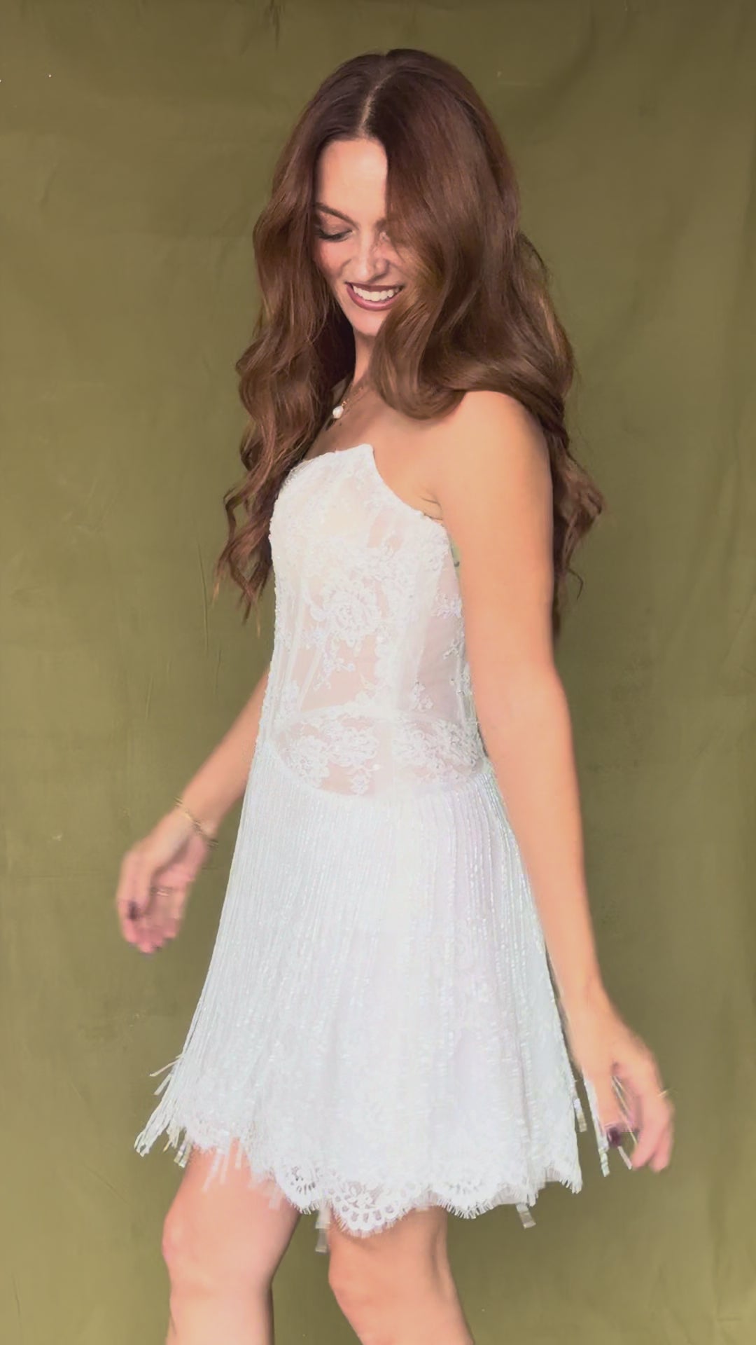 Woman dancing in fringe mini dress in front of green backdrop