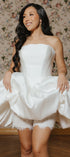 Woman wearing a strapless white wedding dress with a floral wallpaper background