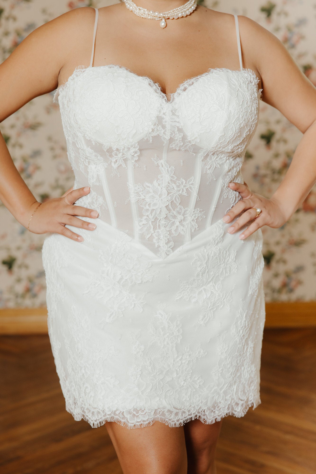 White lace dress worn by a person with a floral background