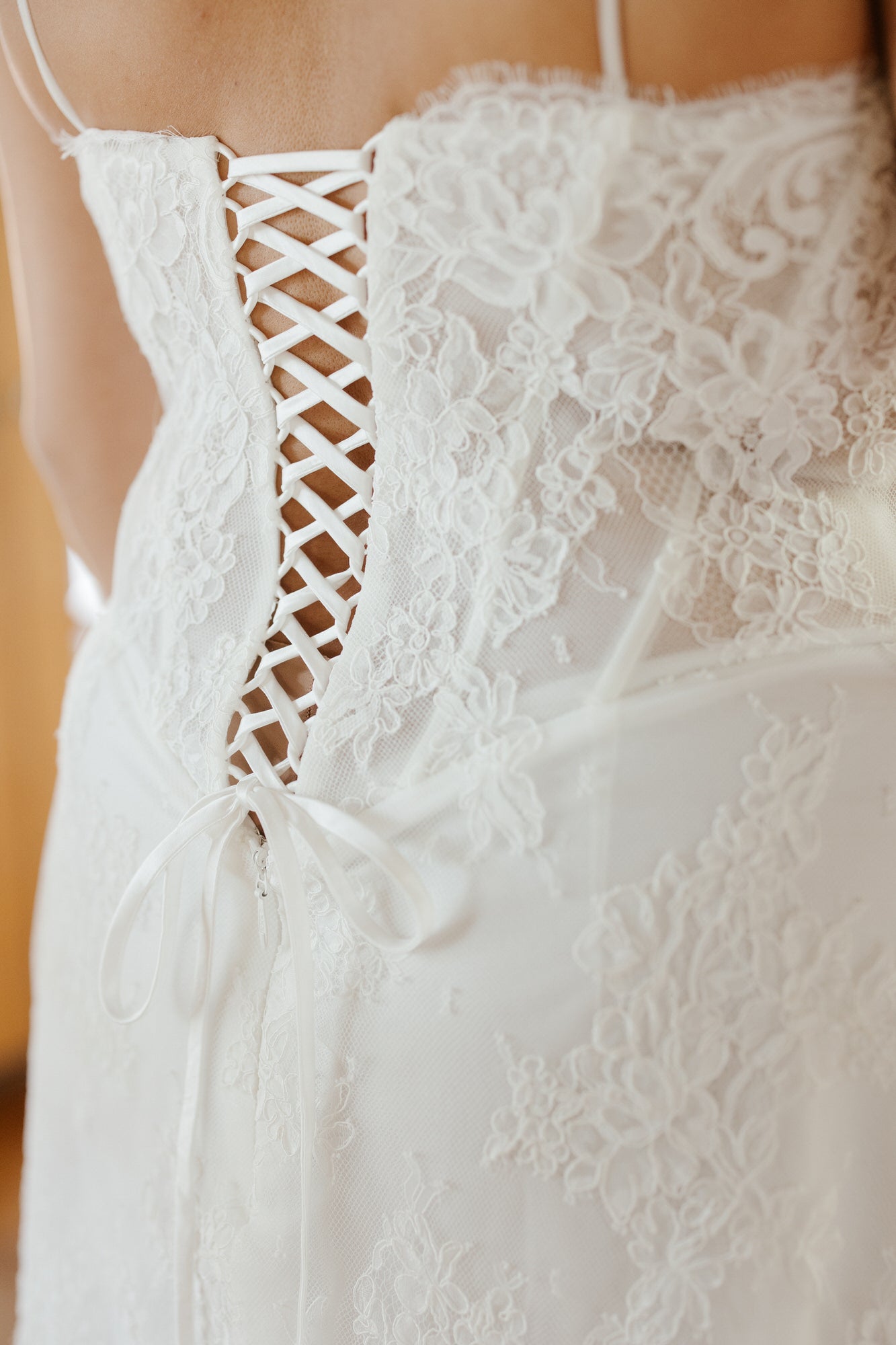 Close-up of a white lace wedding dress with intricate detailing.