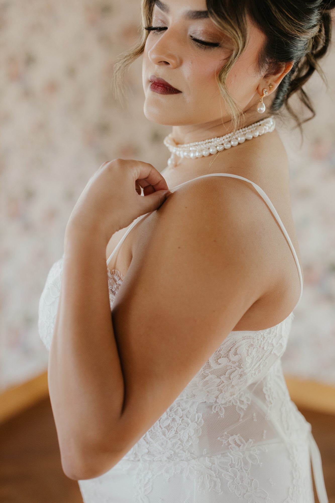 Woman wearing a white lace dress with a blurred floral background