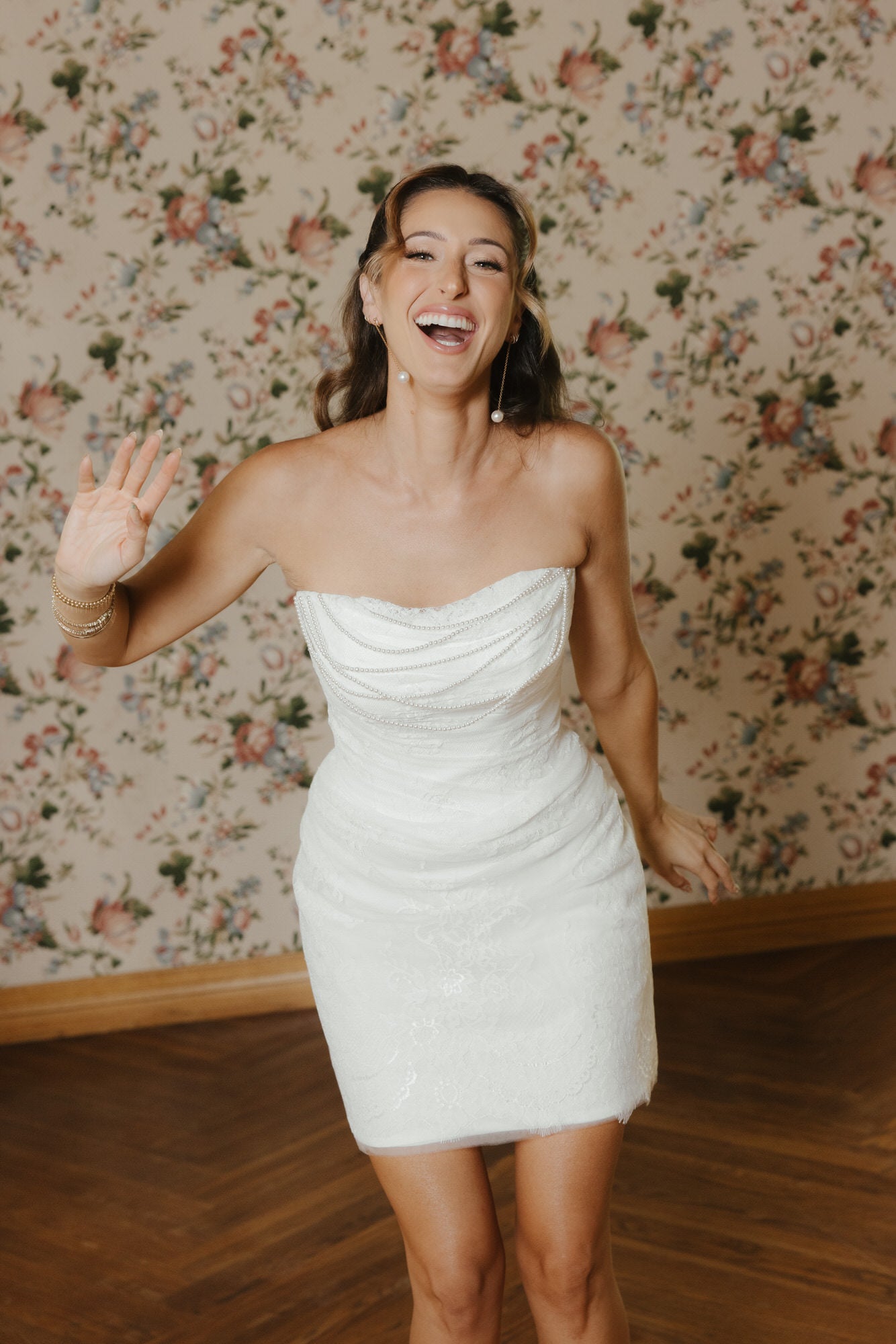 Woman in a white strapless dress standing in front of floral wallpaper