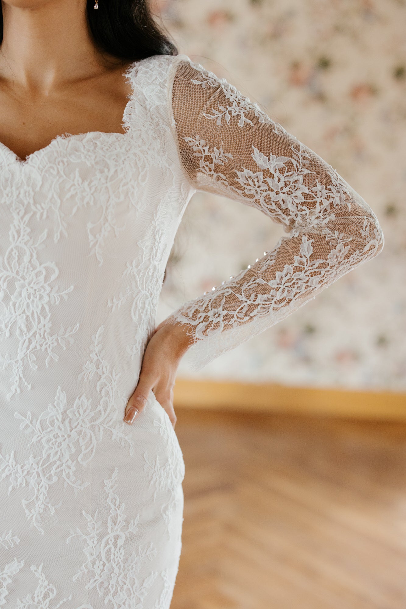 Close-up of a white lace wedding dress with long sleeves.